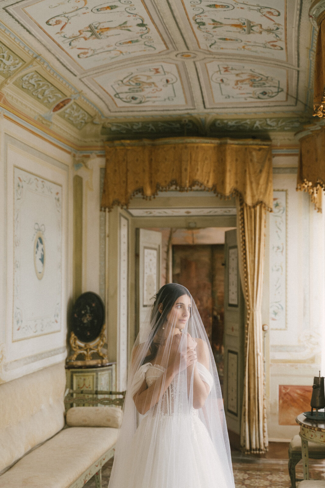 A bride in the doorway of a frescoed room