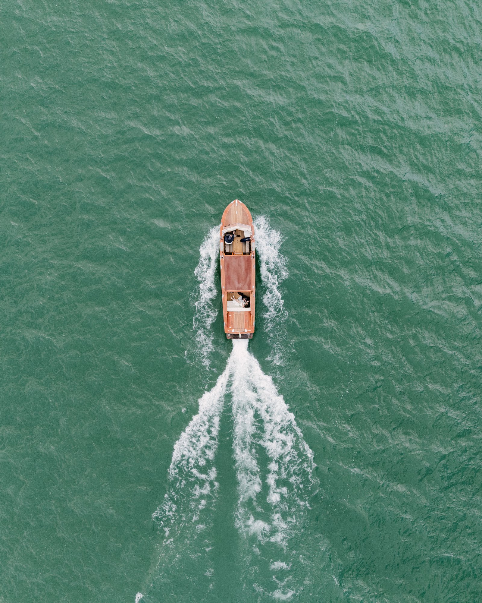 Daisy and Easton crossing Lake Como in a wooden boat, seen from above