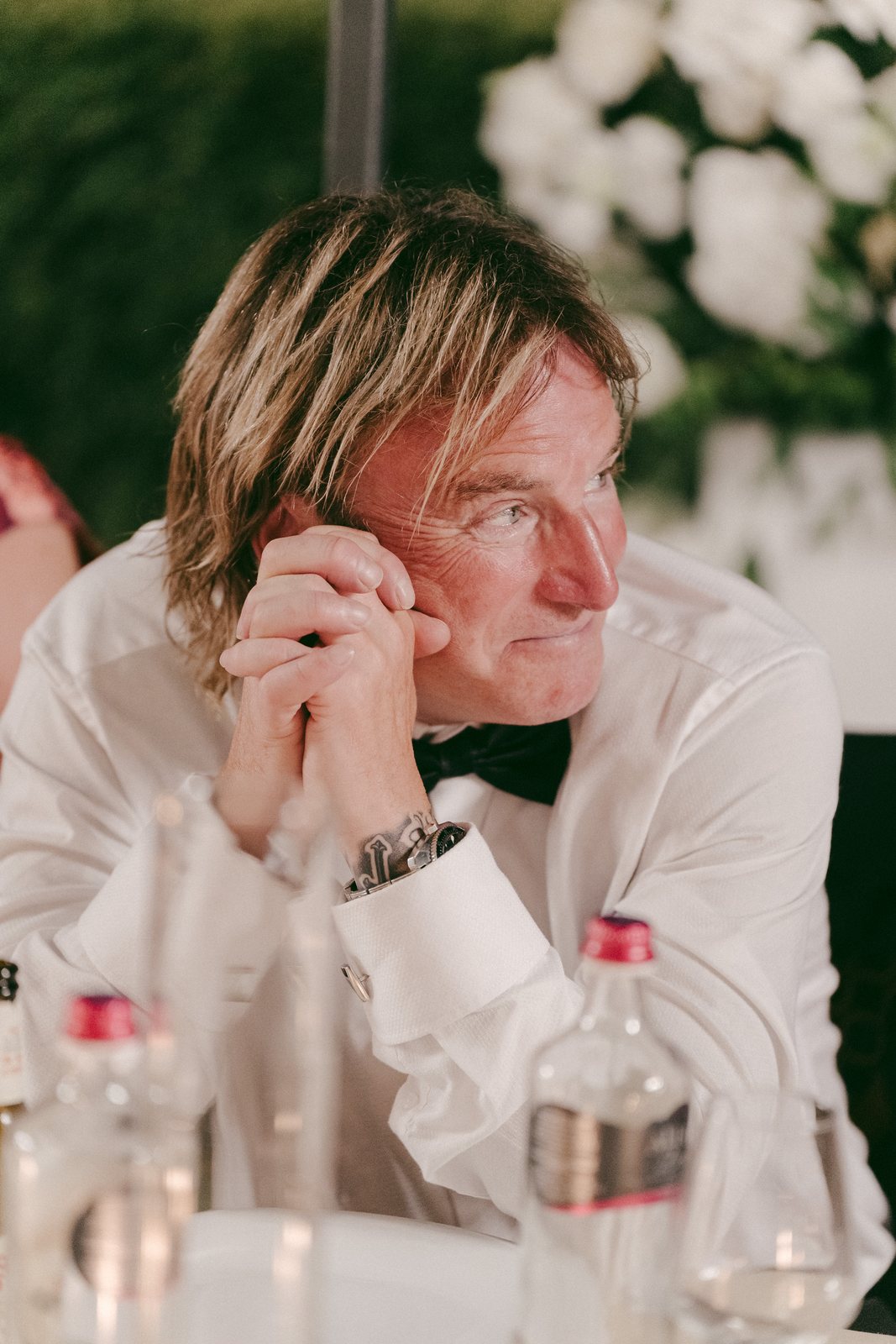 A guest listening to a speech at dinner, hands together